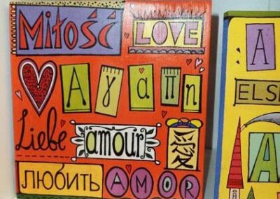 The word 'Love' in many languages painted with bright colors on wood with orange background